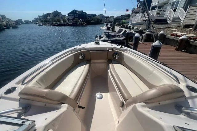 Slide: The Image of 2013 Grady-White Freedom 275 boat with spacious seating, docked in a scenic waterfront area. - 14