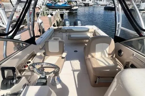 Slide: The Image of 2013 Grady-White Freedom 275 boat interior with beige seating and steering wheel, docked at marina. - 9