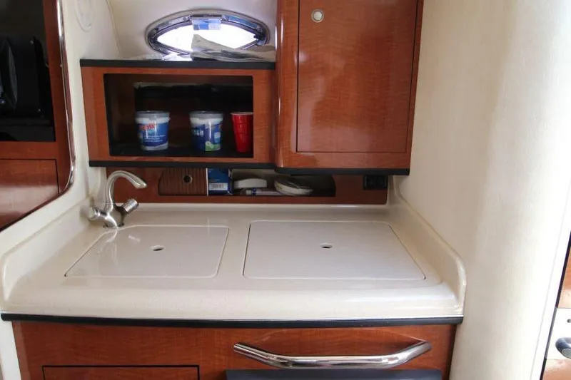 Slide: The Image of 2005 Sea Ray 280 Sundancer interior kitchenette with sink and storage cabinets. - 15