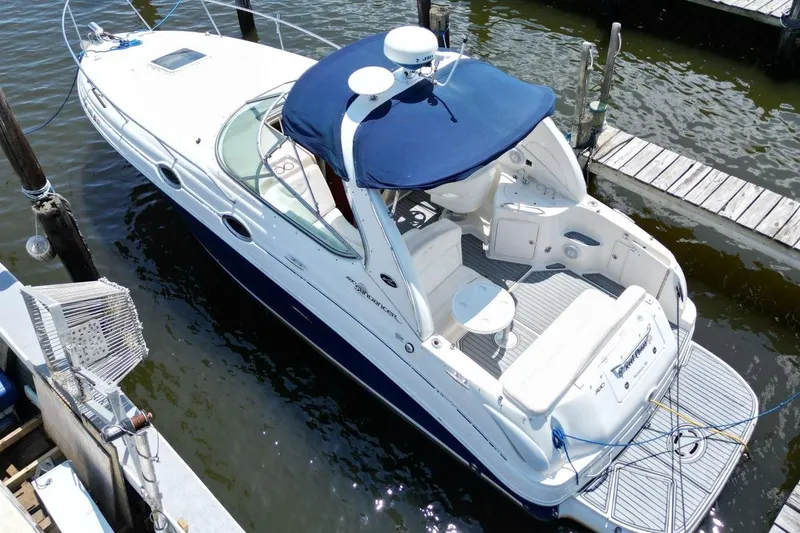 Slide: The Image of 2005 Sea Ray 280 Sundancer docked, featuring a blue canopy and spacious deck. - 6