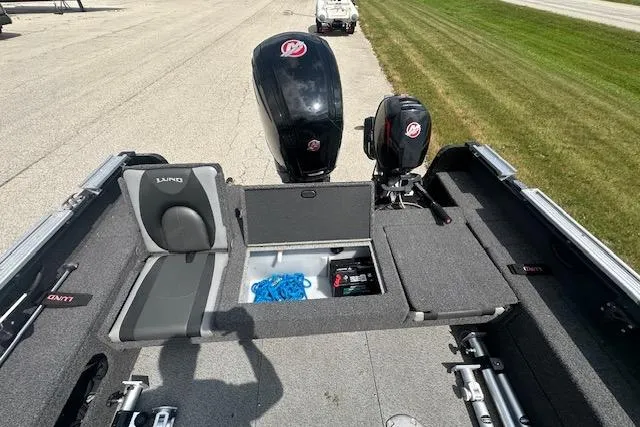 Slide: The Image of 2020 Lund 1775 Adventure Sport boat interior with storage and dual motors on a sunny day. - 3