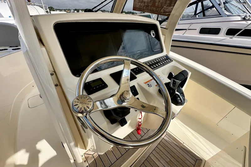 Slide: The Image of 2024 Scout 277 LXF boat helm with steering wheel and control panel. - 12