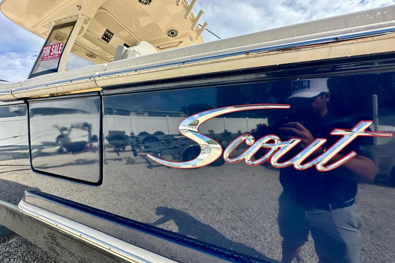 Slide: The Image of 2024 Scout 277 LXF boat with "For Sale" sign, reflecting surroundings. - 2