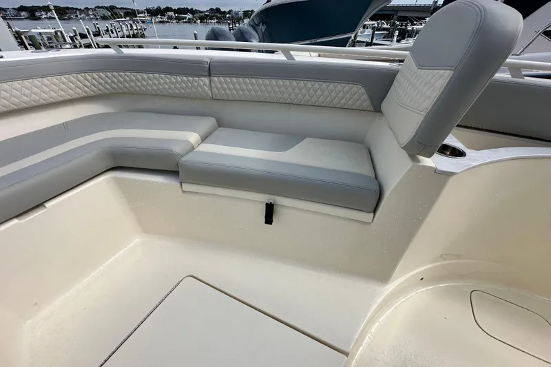 Slide: The Image of 2024 Scout 277 LXF boat interior with cushioned seating and waterfront view. - 26