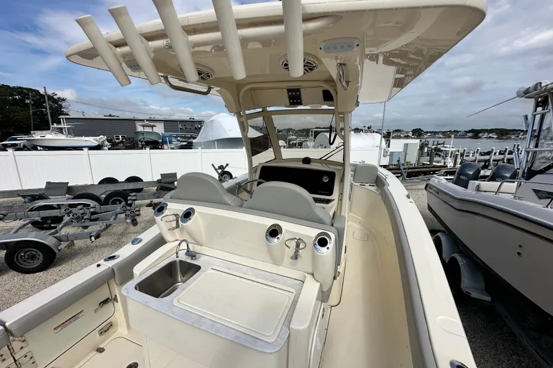 Slide: The Image of 2024 Scout 277 LXF boat interior with helm, seating, and sink at marina. - 29