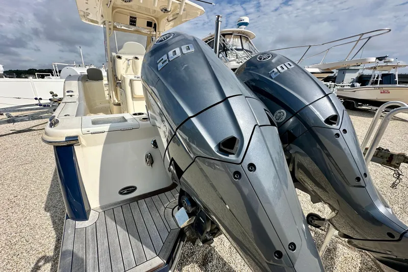 Slide: The Image of 2024 Scout 277 LXF boat with dual 200 horsepower engines, docked under cloudy skies. - 5