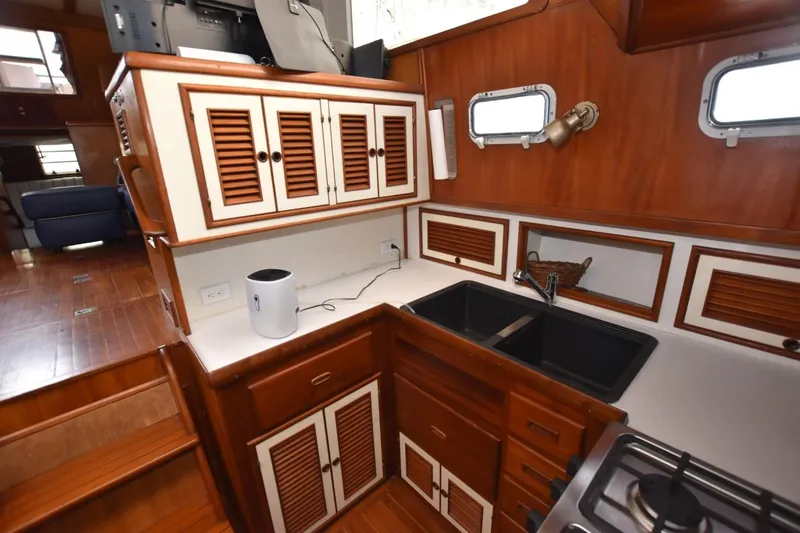Slide: The Image of 1987 Hartman-Palmer Offshore 38 Sundeck kitchen with wooden cabinets and black sink. - 13
