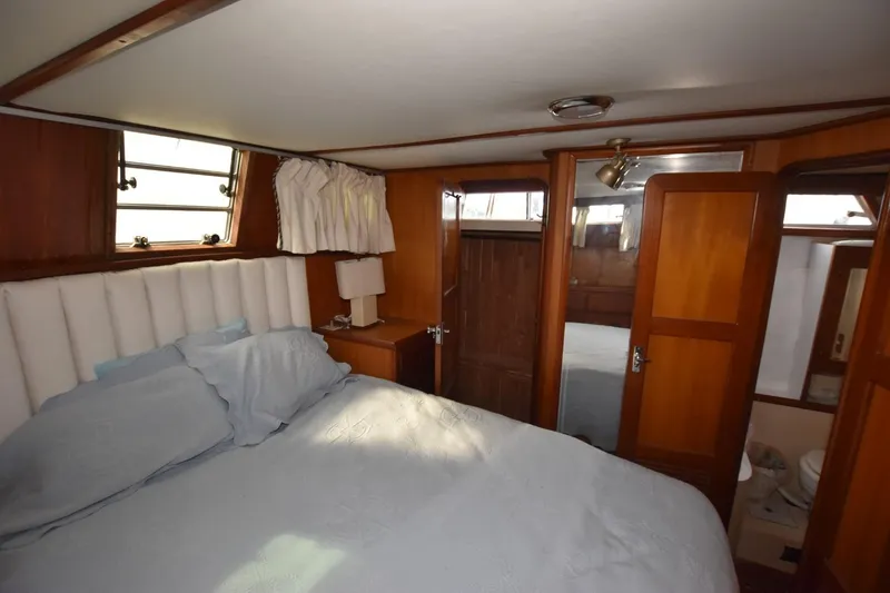 Slide: The Image of 1987 Hartman-Palmer Offshore 38 Sundeck bedroom with wood paneling and cozy bedding. - 20
