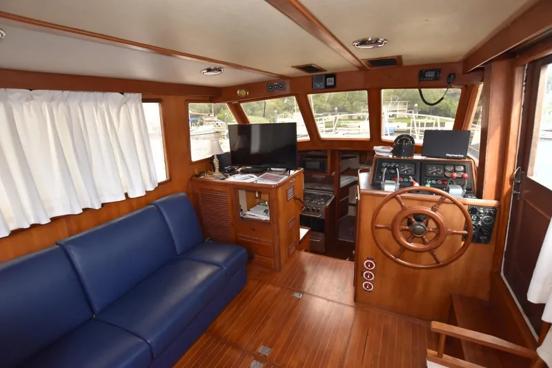 Slide: The Image of 1987 Hartman-Palmer Offshore 38 Sundeck interior with wooden helm, blue sofa, and navigation equipment. - 8