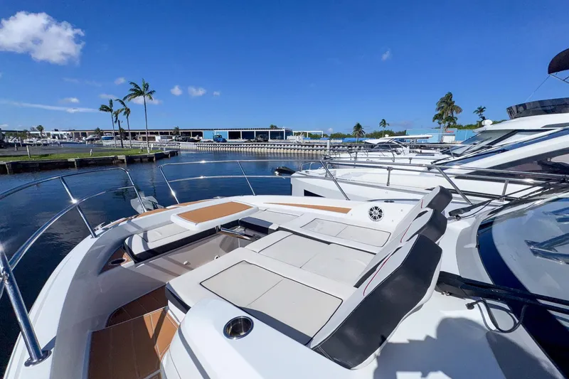 Slide: The Image of 2022 Jeanneau Leader 12.5 WA yacht docked, featuring spacious deck seating under clear blue skies. - 37
