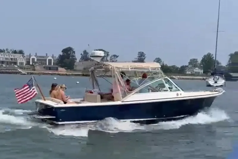The Image of 2013 Hunt Yachts Harrier cruising with passengers, American flag waving, coastal background. - 0