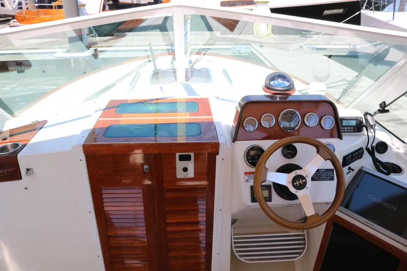 Slide: The Image of 2013 Hunt Harrier boat docked, featuring beige seating and American flag, in marina setting. - 15
