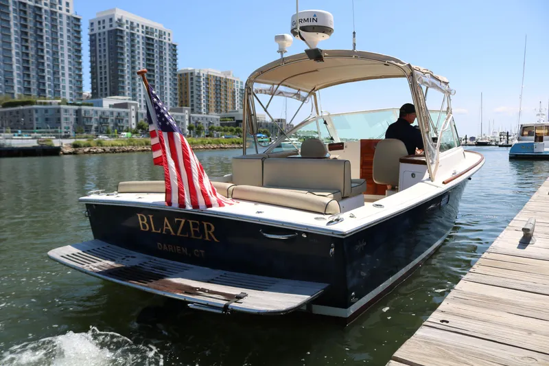 Slide: The Image of 2013 Hunt Harrier boat cruising near modern waterfront buildings. - 2