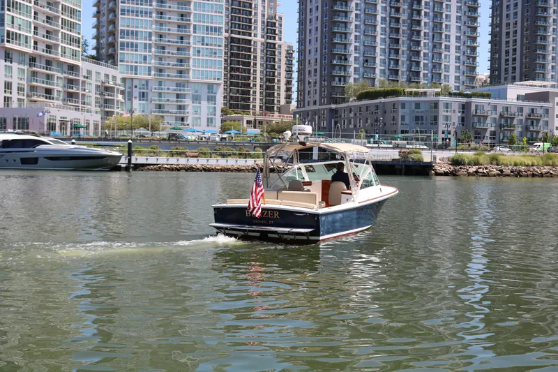 Slide: The Image of 2013 Hunt Harrier boat cruising in urban waterfront with modern high-rise buildings. - 21