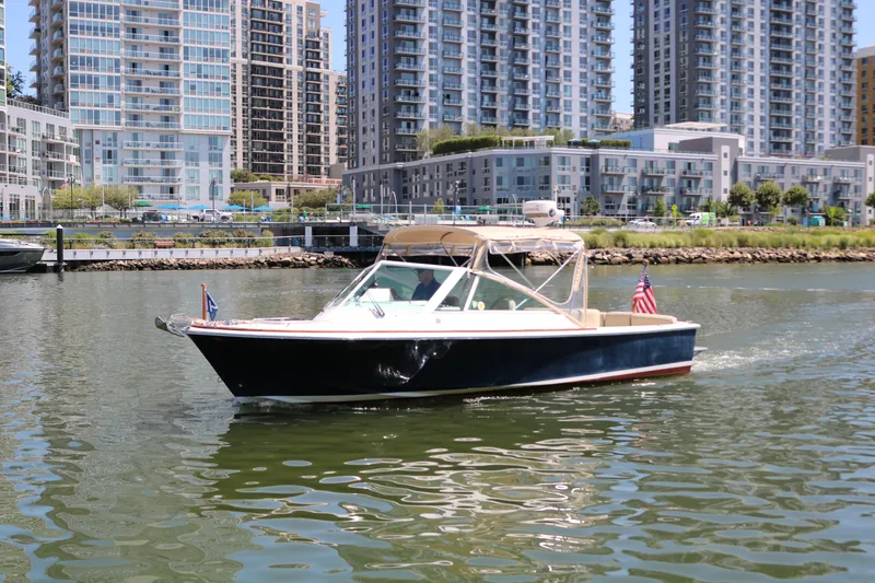Slide: The Image of 2013 Hunt Harrier boat cruising in urban waterfront setting with modern buildings. - 26