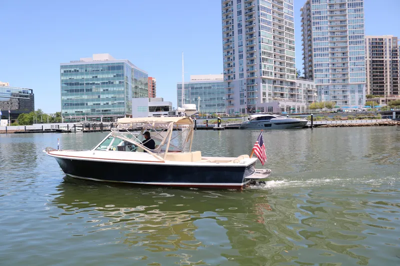 Slide: The Image of 2013 Hunt Harrier boat cruising in urban marina with modern buildings in background. - 28