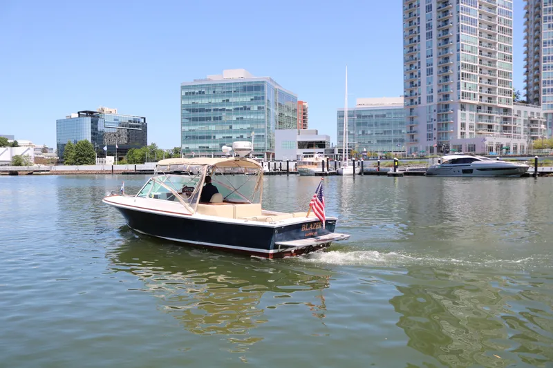 Slide: The Image of 2013 Hunt Harrier boat cruising near modern waterfront buildings. - 29