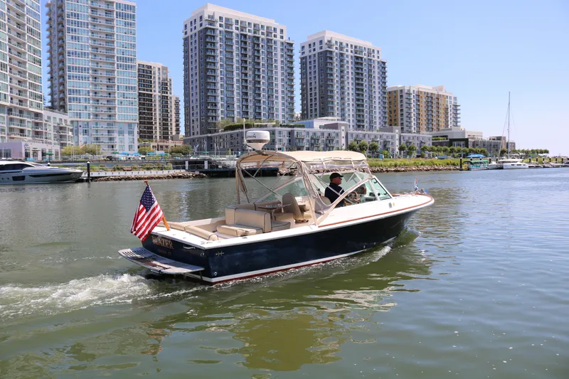 Slide: The Image of 2013 Hunt Harrier boat cruising near modern waterfront buildings. - 36