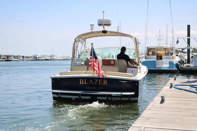 Slide: The Image of 2013 Hunt Yachts Harrier "Blazer" departing dock, American flag displayed, sunny marina setting. - 42
