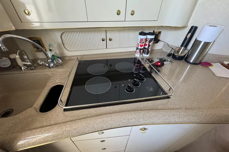 Slide: The Image of 1997 Sea Ray 400 Sundancer kitchen with stove, sink, and countertop accessories. - 10