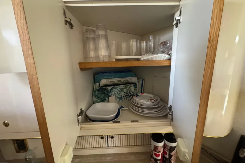 Slide: The Image of Cabinet interior on 1997 Sea Ray 400 Sundancer with dishes and glasses neatly arranged. - 17