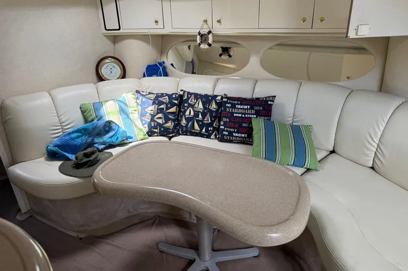 Slide: The Image of Interior of 1997 Sea Ray 400 Sundancer with cozy seating and nautical-themed pillows. - 22