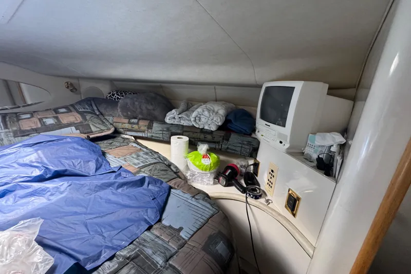 Slide: The Image of 1997 Sea Ray 400 Sundancer cabin interior with bed, TV, and personal items. - 33