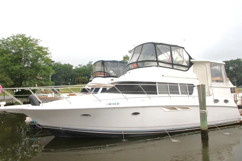 Slide: The Image of 1997 Silverton 402 Motor Yacht docked by a lush, green shoreline. - 2