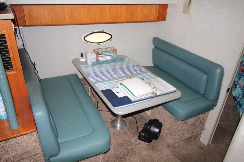Slide: The Image of 1997 Silverton 402 Motor Yacht interior with teal seating and table, featuring nautical decor. - 23
