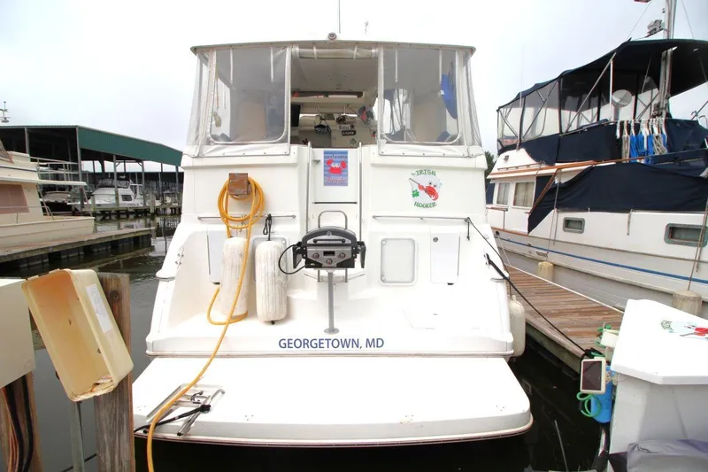 Slide: The Image of 1997 Silverton 402 Motor Yacht docked at marina, rear view with name "Irish Hooker." - 4