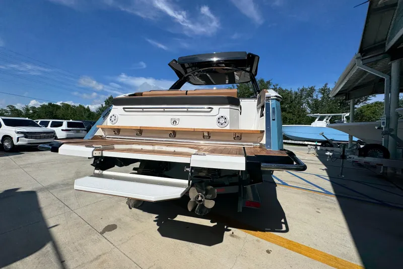 Slide: The Image of 2024 Cobalt R33 boat rear view, showcasing swim platform and sleek design in a marina setting. - 14