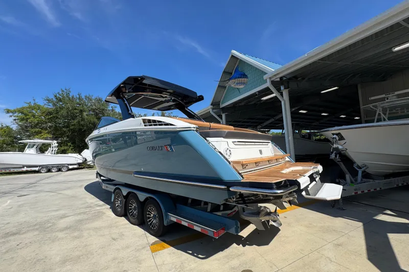 Slide: The Image of 2024 Cobalt R33 boat on trailer, parked outside a marina under clear blue sky. - 19