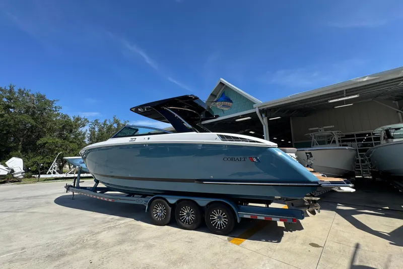 Slide: The Image of 2024 Cobalt R33 boat on trailer under clear blue sky at marina. - 20