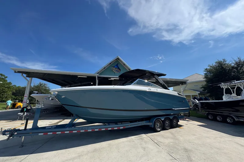 Slide: The Image of 2024 Cobalt R33 boat on trailer under clear blue sky at marina. - 3
