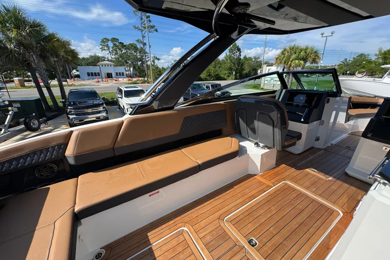 Slide: The Image of 2024 Cobalt R33 boat interior with tan seating and wooden flooring, parked outdoors. - 39
