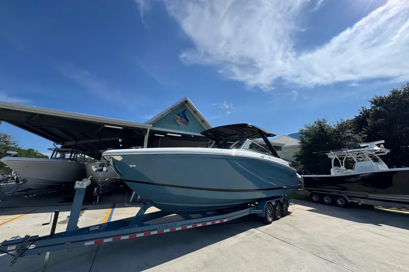 Slide: The Image of 2024 Cobalt R33 boat on trailer under clear blue sky at marina. - 4