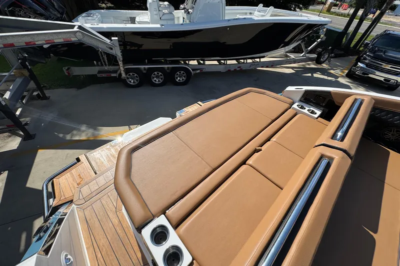 Slide: The Image of 2024 Cobalt R33 boat with tan leather seating and wooden deck, parked near a trailer. - 43