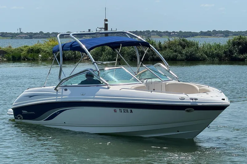 Slide: The Image of 2001 Chaparral 230 SSi boat on a calm lake with lush greenery in the background. - 1