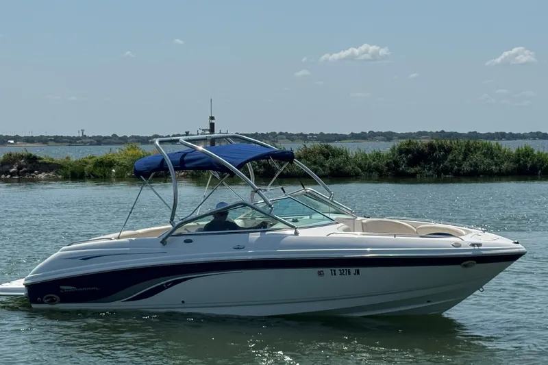 Slide: The Image of 2001 Chaparral 230 SSi boat cruising on a sunny lake with lush greenery. - 3