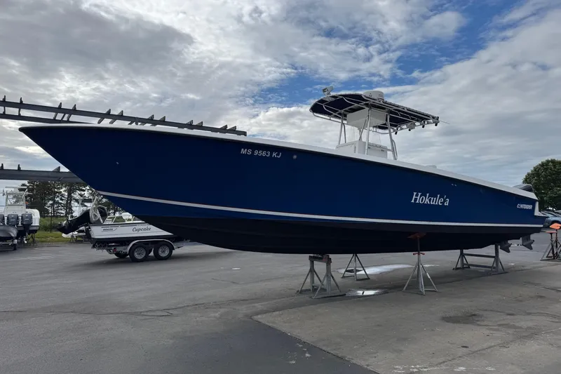 The Image of 2002 Contender 36 Open boat on stands, blue hull, overcast sky background. - 1