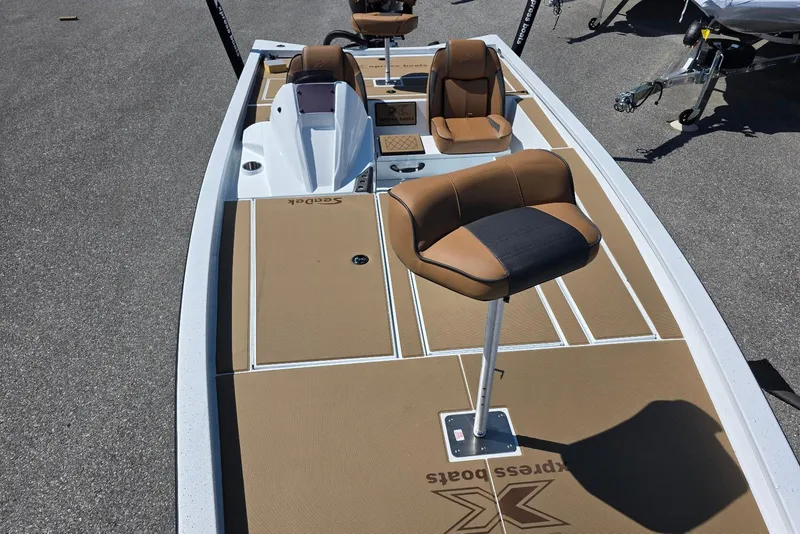 Slide: The Image of 2026 Xpress H20 Bass boat with tan seating and deck, parked on pavement. - 13