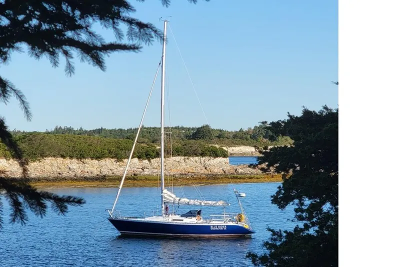 Slide: The Image of Sailboat "Blue Acres" on serene water, surrounded by lush greenery, Peacock 35 model, 1984. - 8