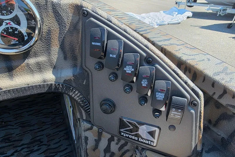 Slide: The Image of Control panel of 2026 Xpress H20 Bass boat with various switches and gauges. - 23