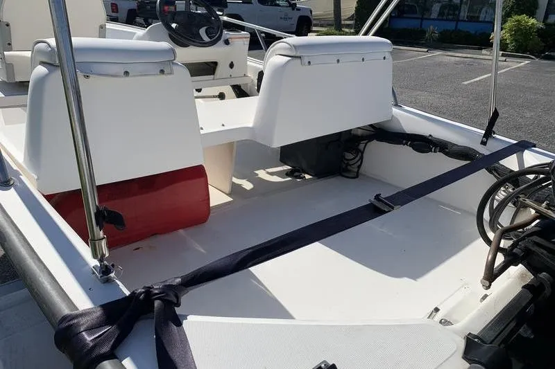 Slide: The Image of 2007 Boston Whaler 130 Sport interior with seating and steering wheel in a parking lot. - 9