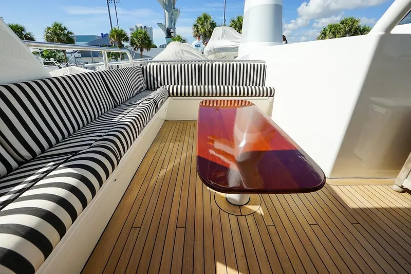 Slide: The Image of Luxurious 1996 ABD 90 Explorer yacht deck with striped seating and polished wooden table. - 91