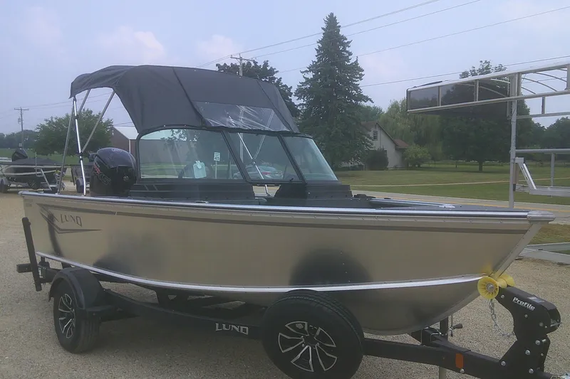 Slide: The Image of 2026 Lund 1800 Explorer Sport boat on trailer, parked outdoors with canopy. - 3