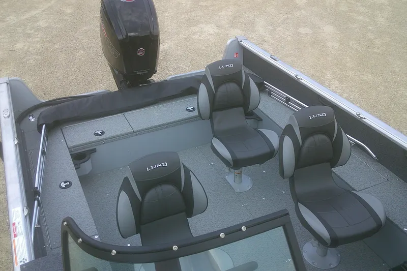 Slide: The Image of 2026 Lund 1800 Explorer Sport boat interior with three black seats and motor. - 9