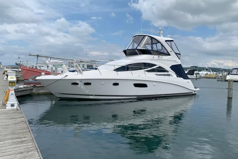 The Image of 2014 Sea Ray 450 Sedan Bridge yacht docked at marina under cloudy sky. - 0