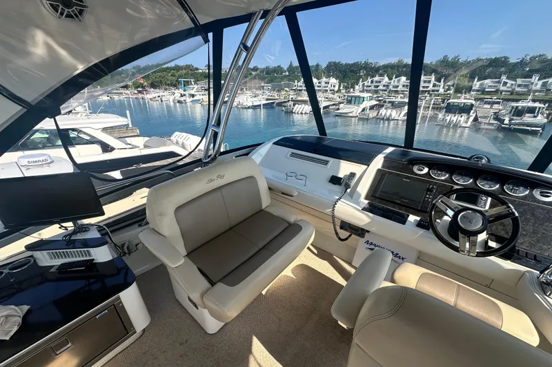 Slide: The Image of 2014 Sea Ray 450 Sedan Bridge helm with marina view, featuring modern controls and seating. - 16