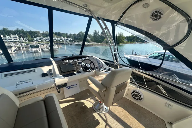 Slide: The Image of 2014 Sea Ray 450 Sedan Bridge helm with marina view, featuring modern controls and seating. - 18